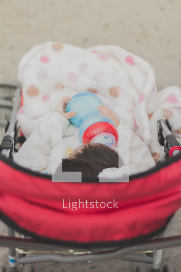 Infant in a stroller with a bottle.