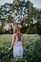 woman in a white romper standing in a field of crops 