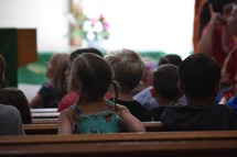 group of young children sitting in church pews listening 
