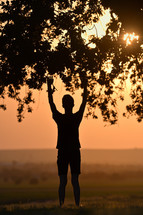 portrait young man praying hands up at sunset