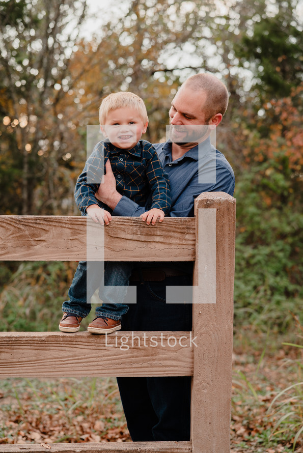 father and son climbing a fence 