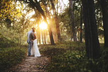 bride and groom hugging on a path in a forest