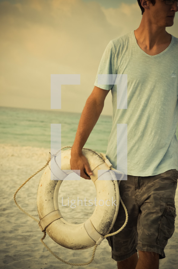 man carrying a life ring on a beach