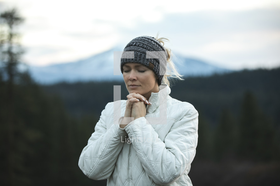 a woman praying on a mountain 