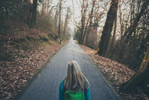 woman looking down a long paved path 