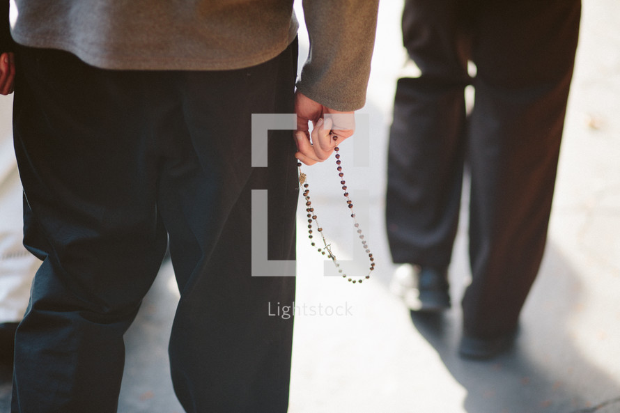Catholic young man walking with a rosary outdoors.