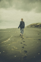 a woman walking barefoot on a beach 