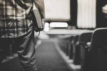 man entering a church and standing in the aisle 