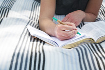 a girl reading a Bible and writing in a journal 