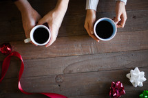 Hands holding coffee cups on a wooden table