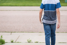 teen boy walking carrying a Bible 