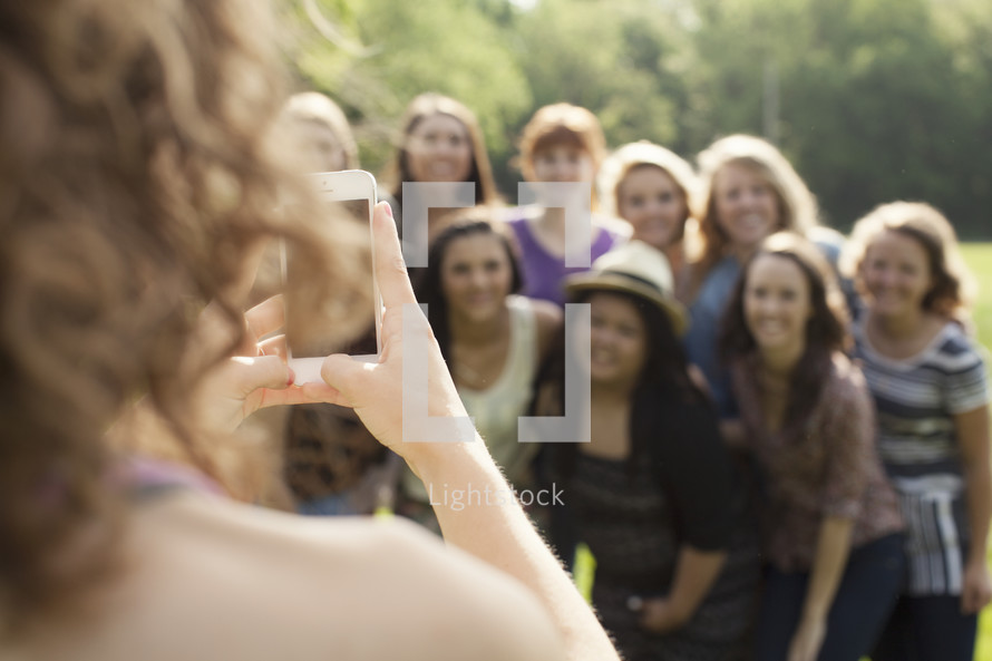 Teenage girl taking a picture of a group of young teen women.