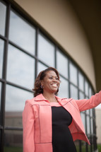 African-American woman standing at a church entrance welcoming others 