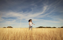A woman running through a field with the sky overhead