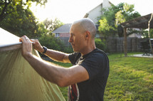 Father setting up a tent in the backyard. 