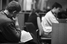 man reading a Bible in his lap at a Bible study 