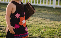 toddler girl in a dress carrying a Bible 