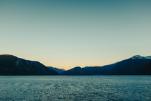 a lake surrounded by mountains at dusk 