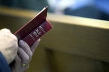 man reading a Bible in a church pew 