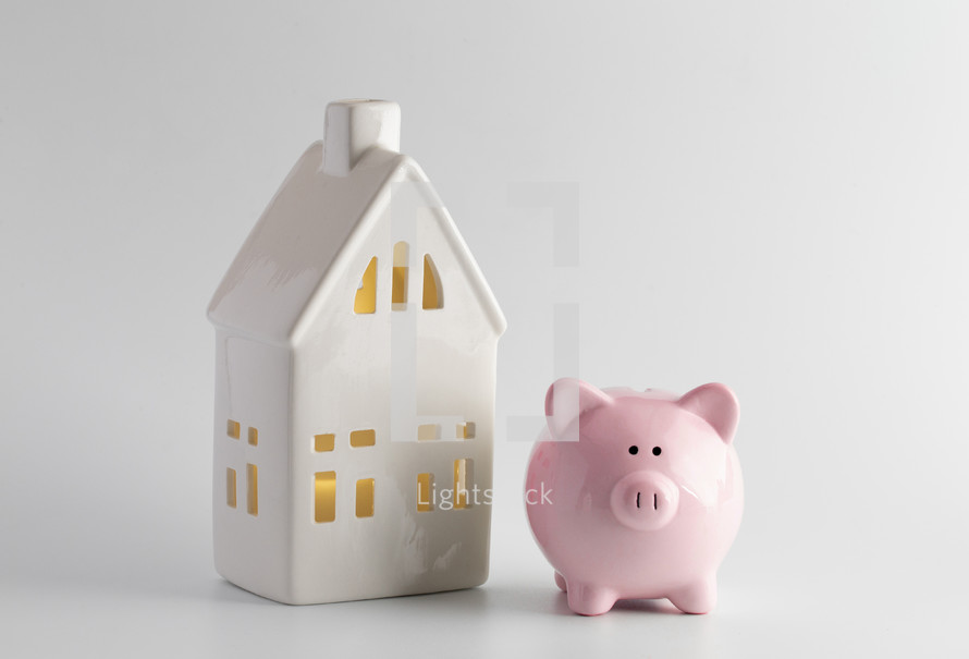 piggy bank and small white house against a white background 