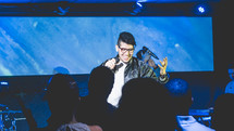 a man singing on stage during a worship service 