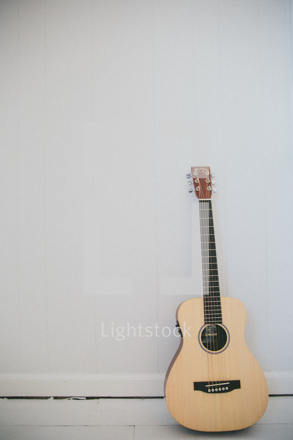 acoustic guitar leaning against a wall 