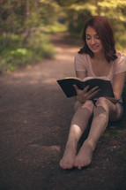 woman sitting outdoors reading a Bible 