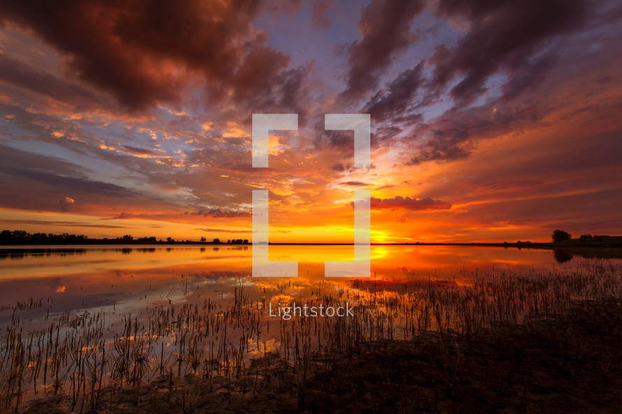 orange sky at sunset reflecting on lake water 
