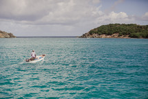 man on a boat traveling through an inlet 