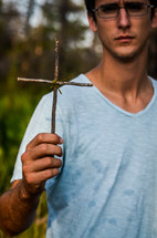 man holding a cross made from sticks
