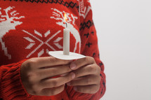 girl in a Christmas sweater holding a candle 