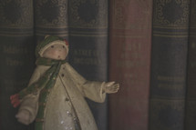 A winter man figurine in front of books on a shelf 