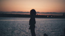 silhouette of a woman standing on a beach at dusk 
