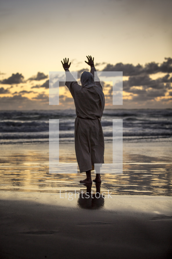 Jesus with raised hands on a shore at sunset 