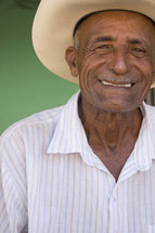 headshot of a smiling man in a hat 