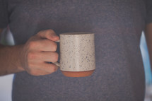 A hand holding a white coffee mug
