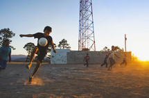 children playing soccer in the dirt 