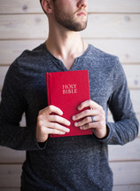 A young man holding a red Bible.
