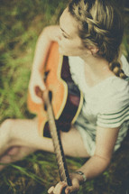 a woman playing a guitar outdoors 