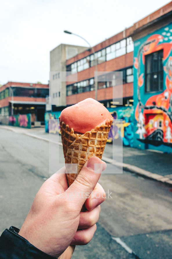 a man holding an ice cream cone in a city 