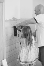 father and daughter using a nail gun to put up shiplap 