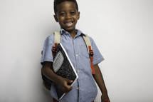 a boy with a book bag holding a composition notebook 