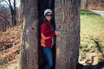 a woman hiding in a tree trunk 