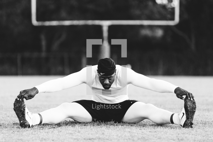 a man stretching on a football field 