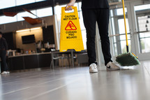 man with a dust mop and wet floor sign 