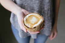 woman holding a coconut with coffee and creamer 