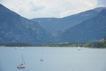 sailboats on the water in front of a mountain backdrop 