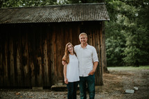 couple standing in front of a barn 