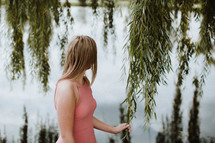 woman touching weeping willow branch by a pond 