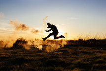man running and jumping with a smoke flare 